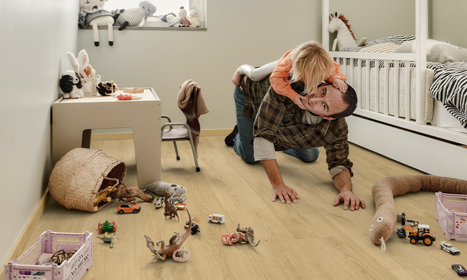 Vater spielt mit Tochter im Kinderzimmer, in dem sich viele Spielzeuge befinden